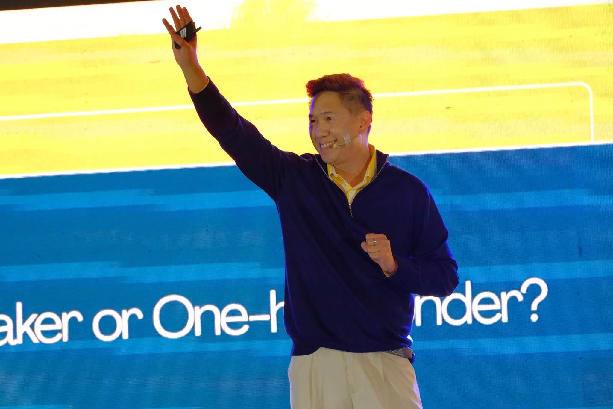 Adrian on stage with a colorful screen behind him
